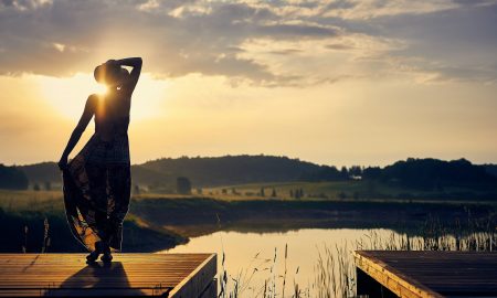 Go with the flow - Silhouette of woman standing on brown wooden dock during sunset.